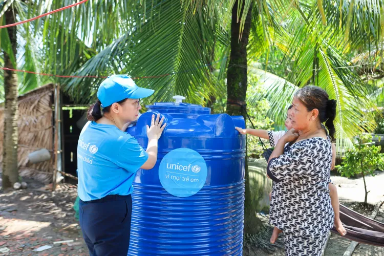 Ng&agrave;y 7 th&aacute;ng 10 năm 2026, x&atilde; Biển Bạch, tỉnh C&agrave; Mau, Việt Nam &ndash; Chị Nguyễn Hồng Hạnh, C&aacute;n bộ Nước sạch, Vệ sinh v&agrave; Vệ sinh c&aacute; nh&acirc;n (WASH) của UNICEF tại Việt Nam, tr&ograve; chuyện với b&agrave; Danh Thị Mai, người đang bế đứa ch&aacute;u &uacute;t của m&igrave;nh, b&ecirc;n cạnh một bồn chứa nước dung t&iacute;ch 1.000 l&iacute;t do UNICEF hỗ trợ tại gia đ&igrave;nh.