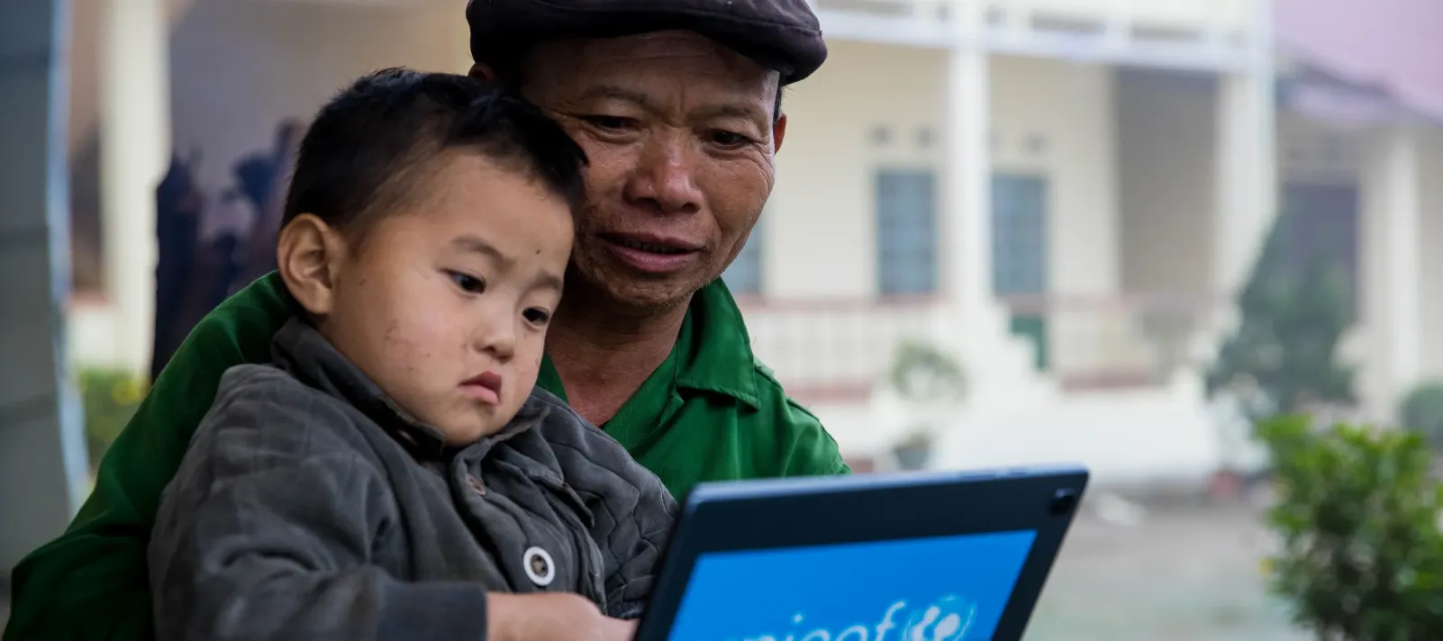 The father and his son are playing a game on tablet 