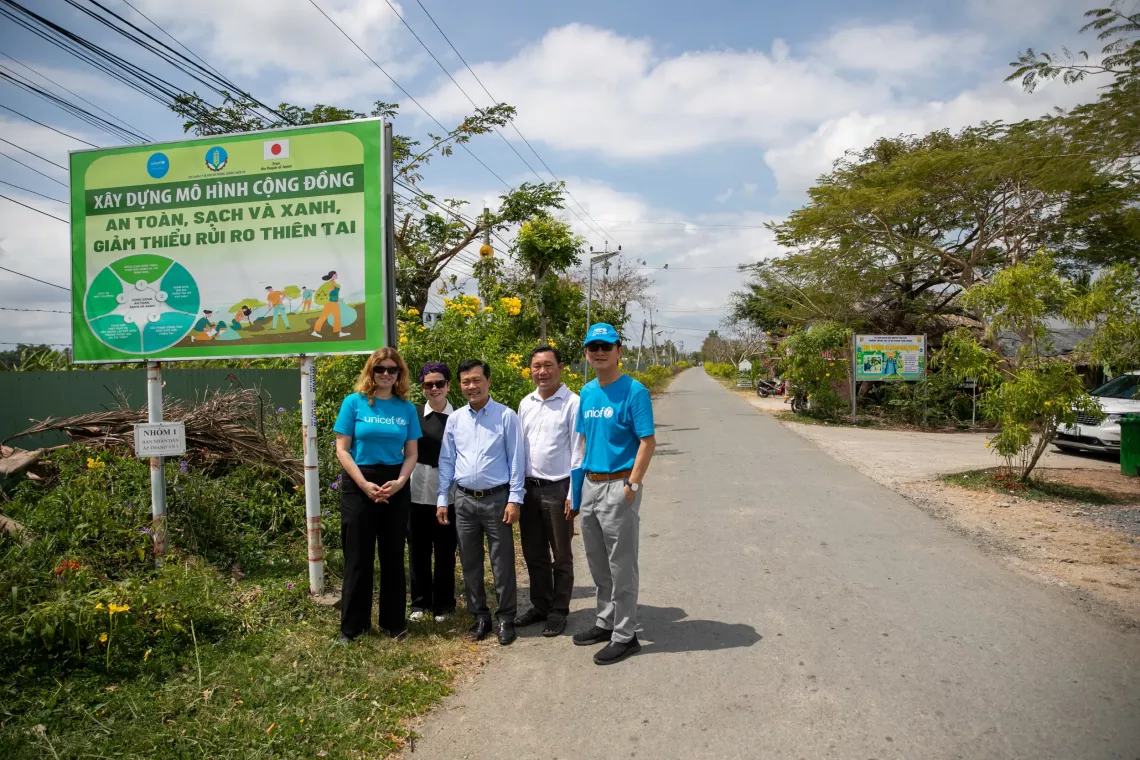 Representatives from UNICEF, VDDMA, and local authorities with the signboard of the Safe, Green and Clean Community initiative