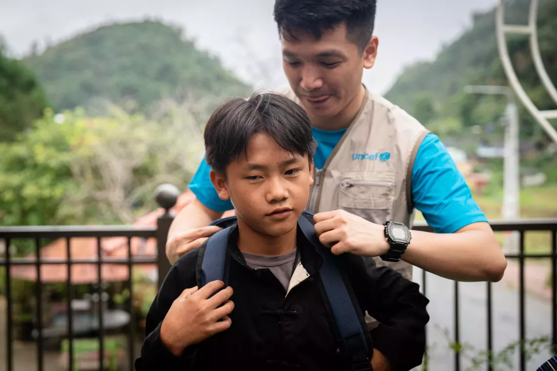 UNICEF staff helps Thao Seo Ha putting on his new bagpack.