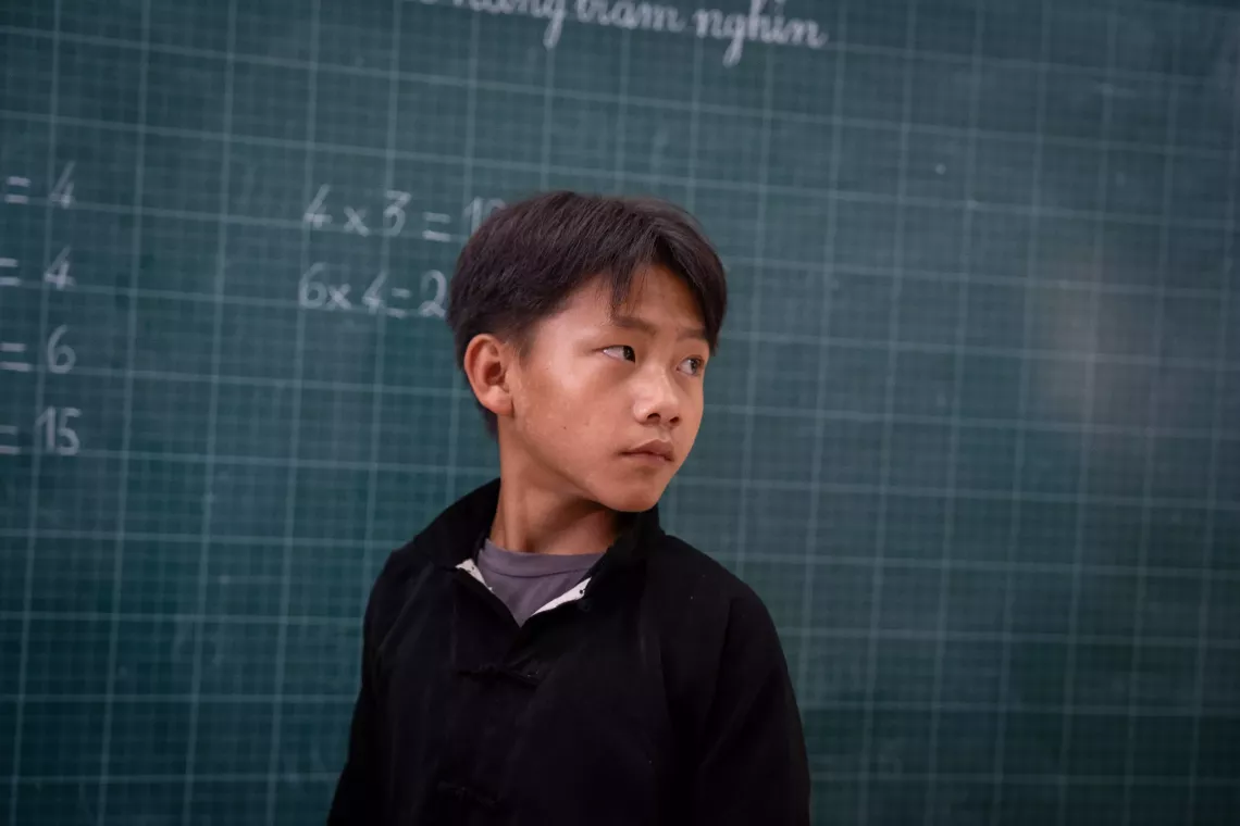 Thao Seo Ha stands in front of a blackboard in his classroom.