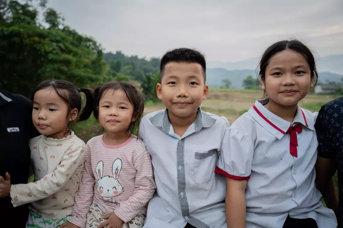 Thuy and Thuong, the 4-year-old twins, sit on the fence of the garden with Bien, 7 years old, and Ngoc, 10 years old (from left to right).