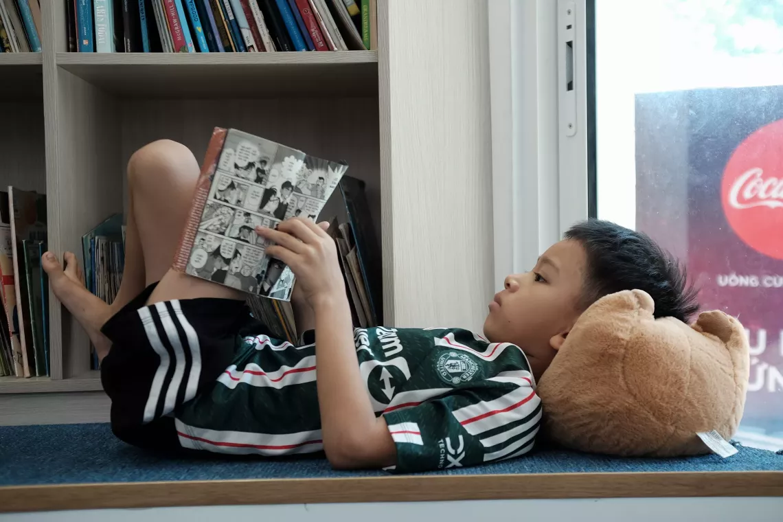A boy lying down and reading.