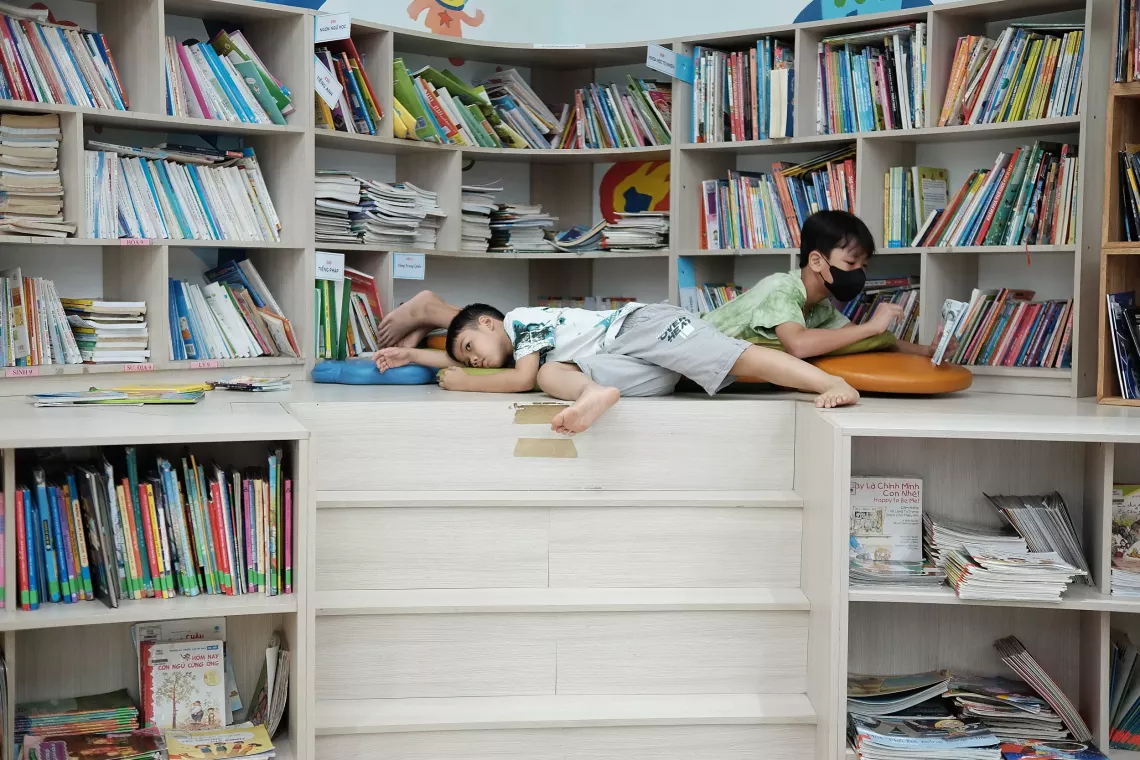 Two boys lying in opposite directions in a library.