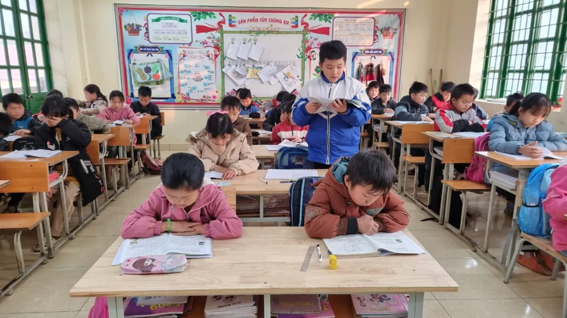 Viet (standing) reads out loud in a class session.