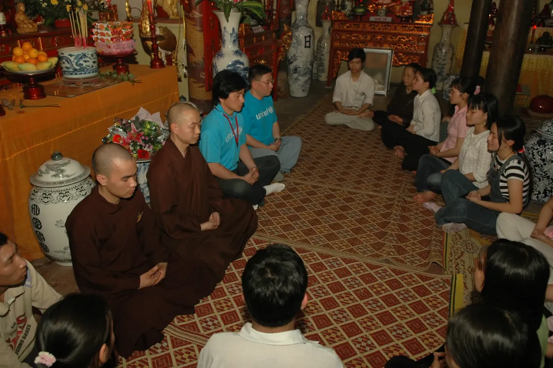UNICEF Goodwill Ambassador Jackie Chan (centre left, in a UNICEF t-shirt) meditates with Buddhist monks and children in 2005 at Phap Van Pagoda in Hanoi. 