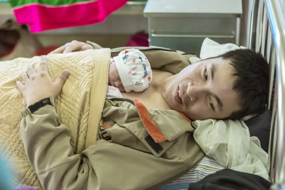 Father Pham Van Dat providing kangaroo care to one of his twins, both born slightly underweight, at northern Dien Bien province&rsquo;s general hospital.