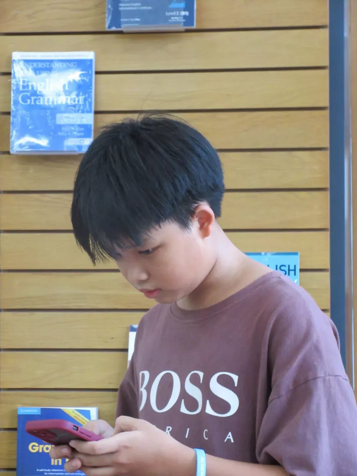 A boy using his phone in a library