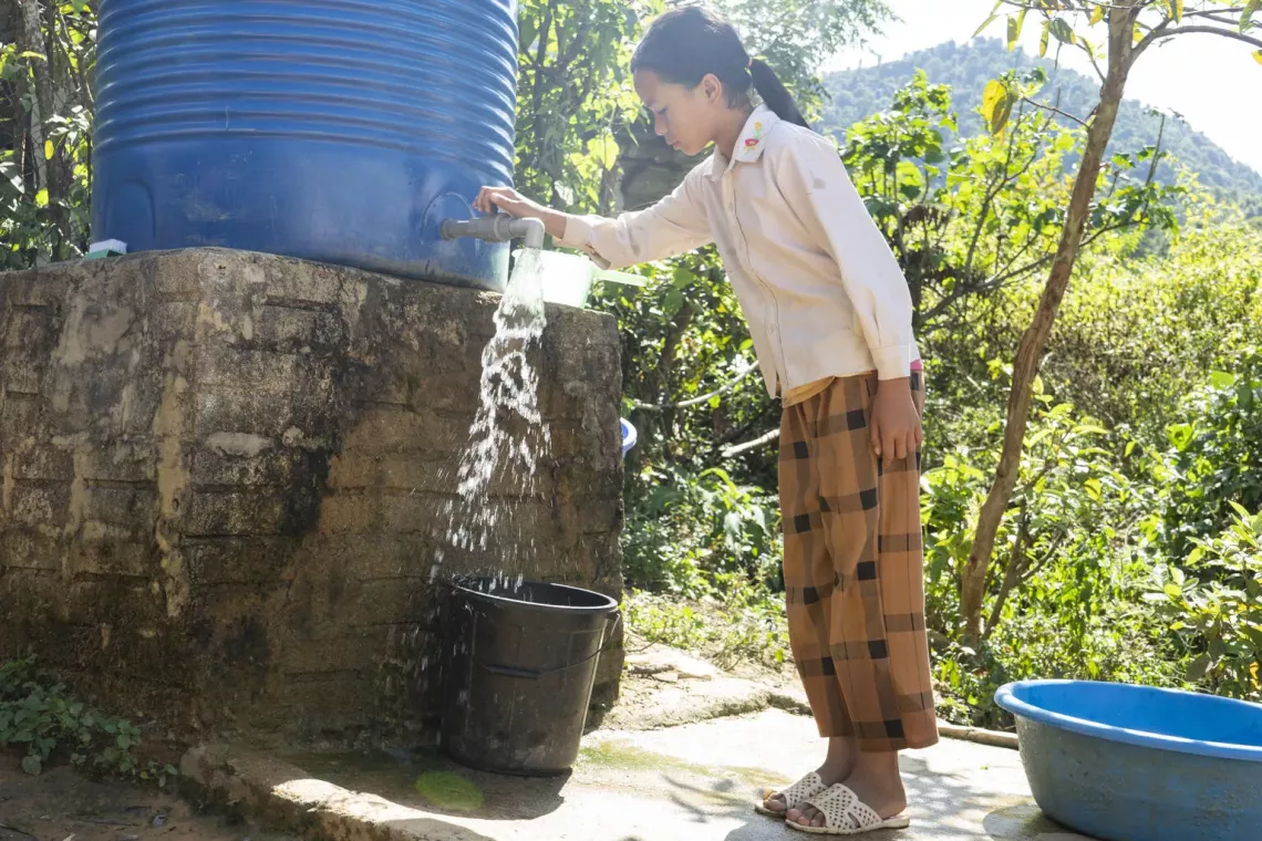 Em b&eacute; g&aacute;i sử dụng nước sạch từ bồn chứa nước hỗ trợ bởi UNICEF