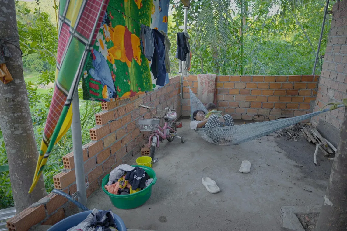 Bi and her 11-month-old brother, Bối Bối, play on a hammock in the space Loan hopes to complete as a bathroom one day.