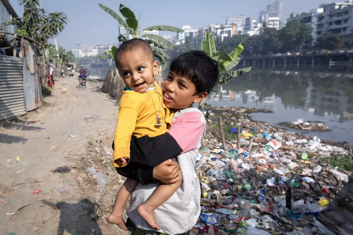Picture of a boy carrying his baby brother. 
