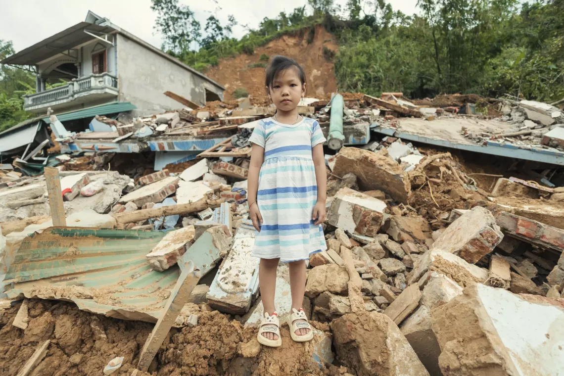 A young girl stands in the rubble of her home which was destroyed in a landslide cause by Super Typhoon Tagi.
