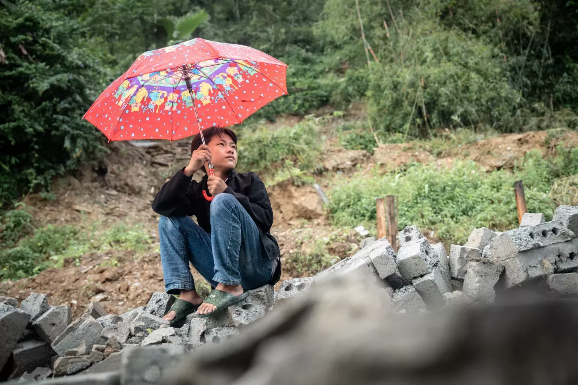 A boy sitting on the ruin of his home