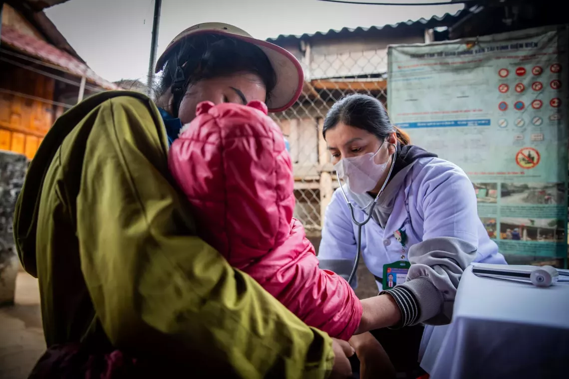Truong Thi Lan Anh, Deputy Head of Keo L&ocirc;m Commune Health Centre, conducts a screening examination for Lo Minh Tuan Ut, a 2-year-old child, during a mobile vaccination session in Suoi Lu Hamlet, Dien Bien Province.