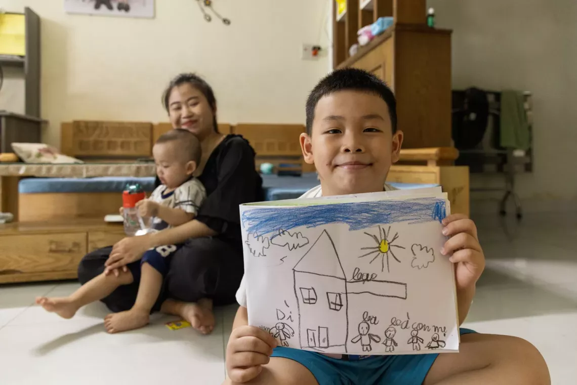 The family of Ms. Lưu Thị Kim Phương (28 years old, housewife) has two children, Đặng Quang Vũ ( 7 years old) and Đặng Quang Hải (14 months old).  Phương mainly spends her time at home caring for and raising her two children. In the photo, it is time to feed Hải. Vũ is on summer vacation, he likes to draw, sing, and play with his young brother.  This is one of the families in group 42, Hoa Phat ward, Da Nang City, that has participated in group sessions of Integrated Early Childhood Development (IECD) Holis