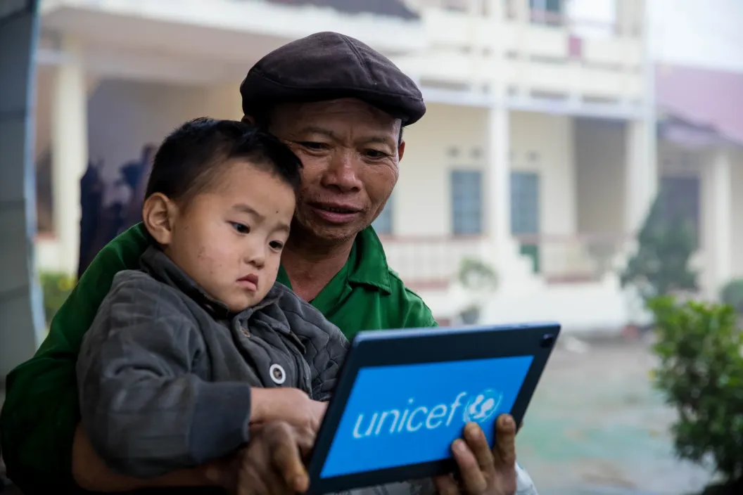 The father and his son are playing a game on tablet 