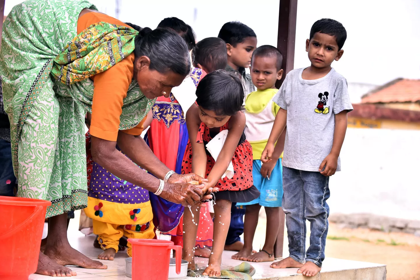 Anganwadi worker help Chidren clean hand before eating  breakfast.