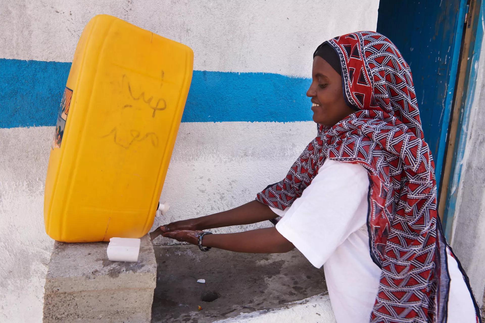 Standing outside a communal sanitary latrine, a woman wash her hands with soap in the village of Abdoya. Djibouti.