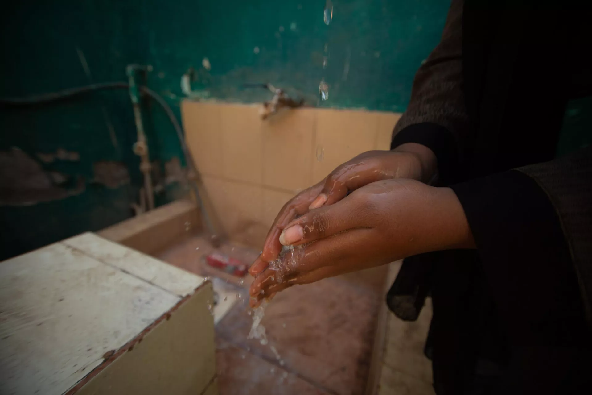 A woman washes her hands with soap and water.