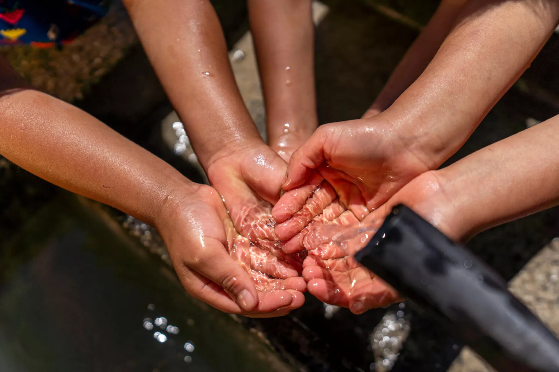 Feliciana Cedillo, a community leaders and agents of change trained by UNICEF, shows how to wash their hands in a community sink to Margarita, Yolanda and Marta on the streets of Chajul, Quiche, Guatemala.