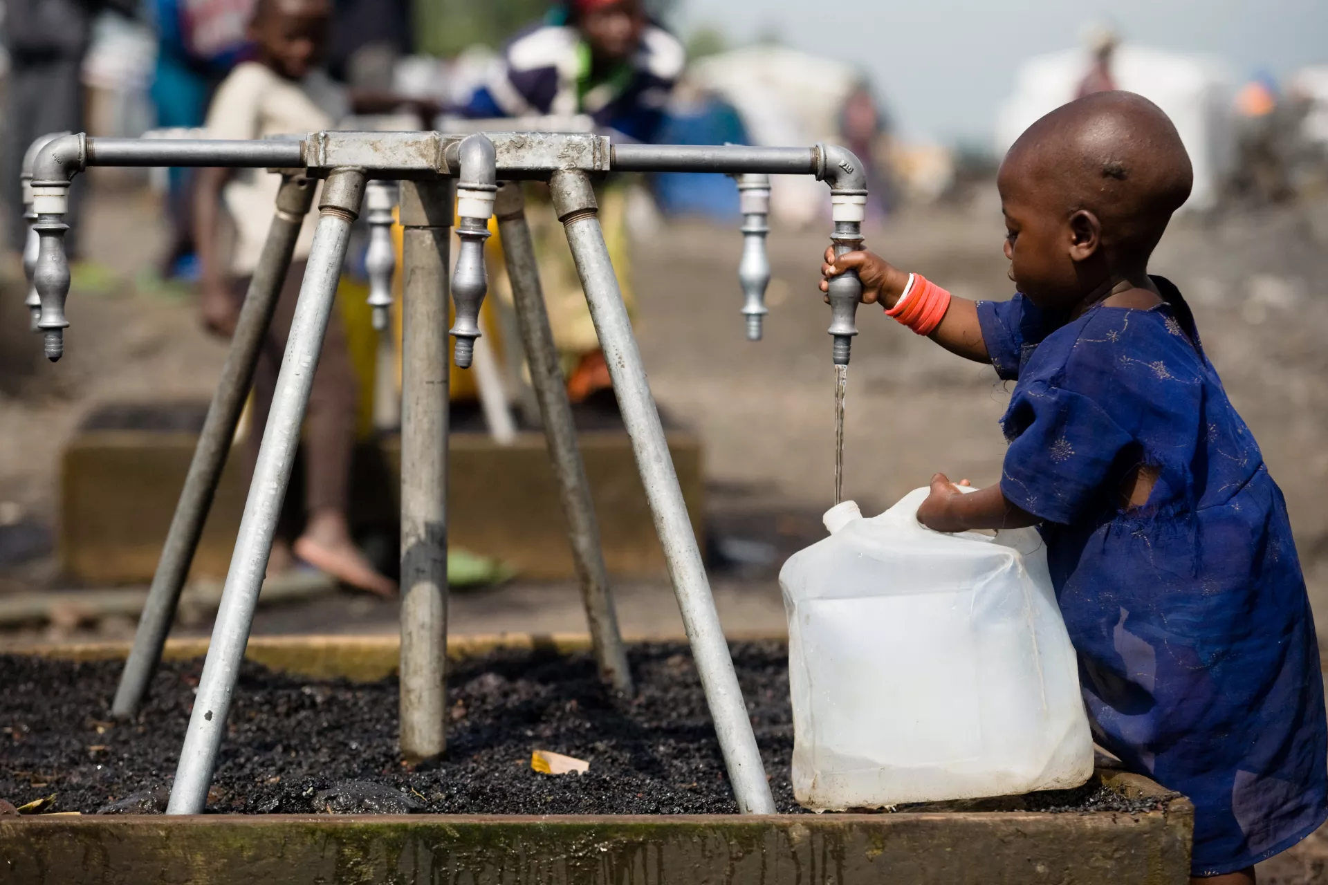 A small child fills a collapsible jerrycan with safe water at one of several outdoor taps in a Kibati camp for the displaced, near Goma, capital of North Kivu Province.