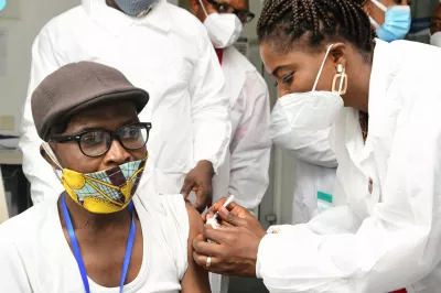 Journalist wearing a mask against COVID-19 getting vaccinated by a nurse