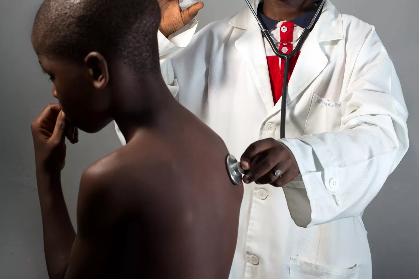 A young boy dress in a doctor's uniform pretends to consult another young boy.