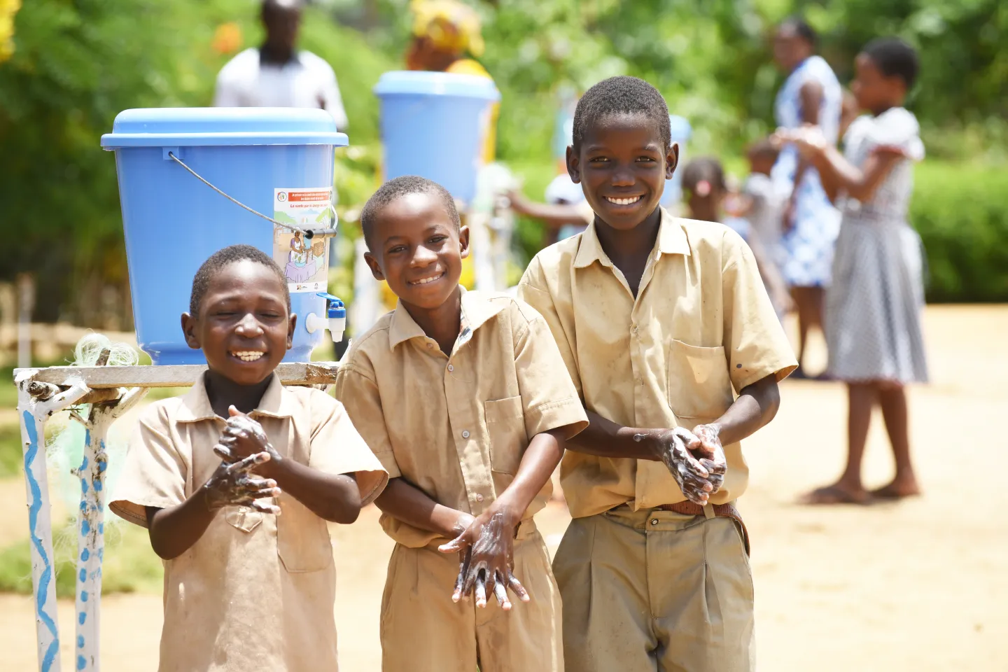 Students smile as they wash their hands