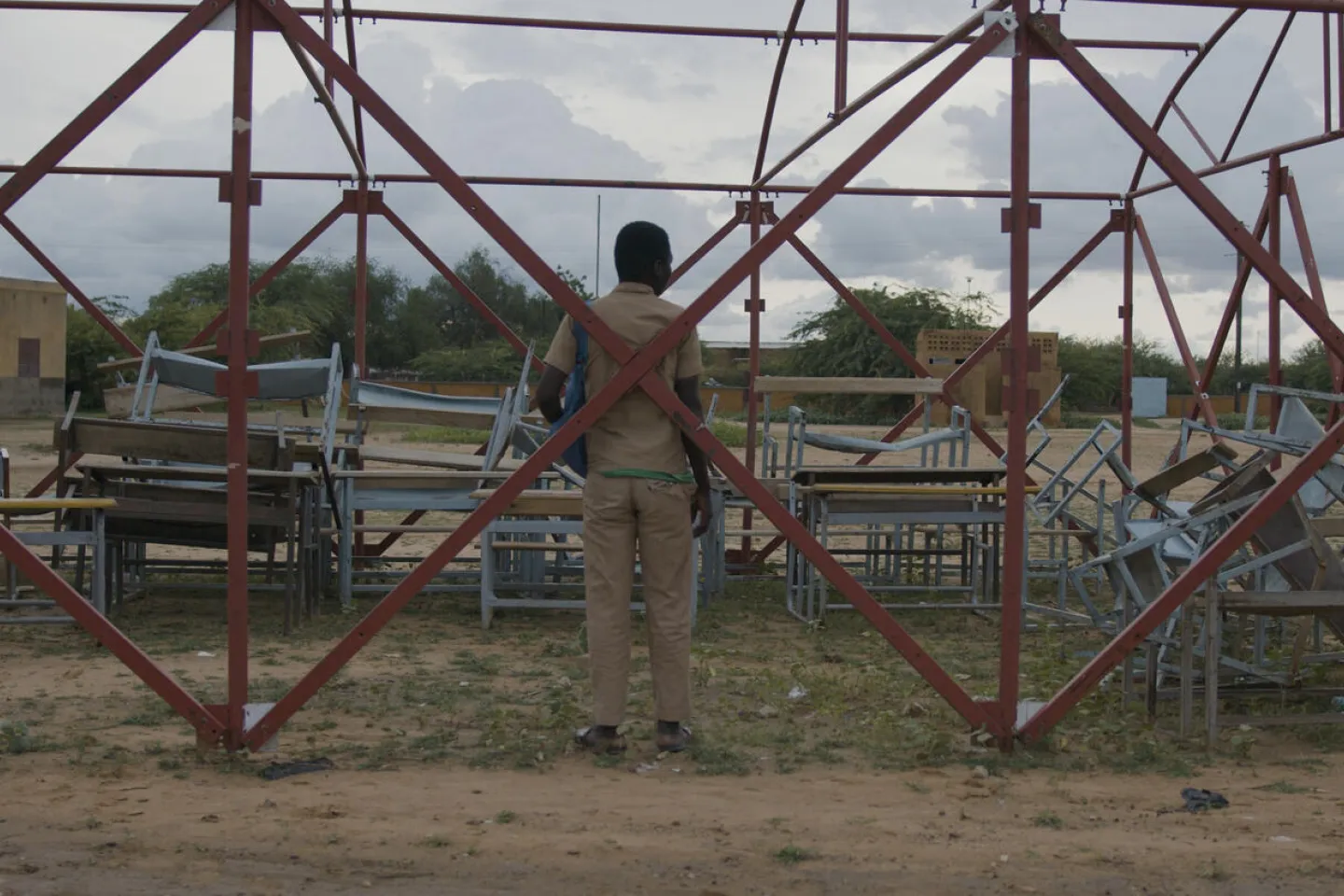 Young boy standing, back to the camera, looking at his old school