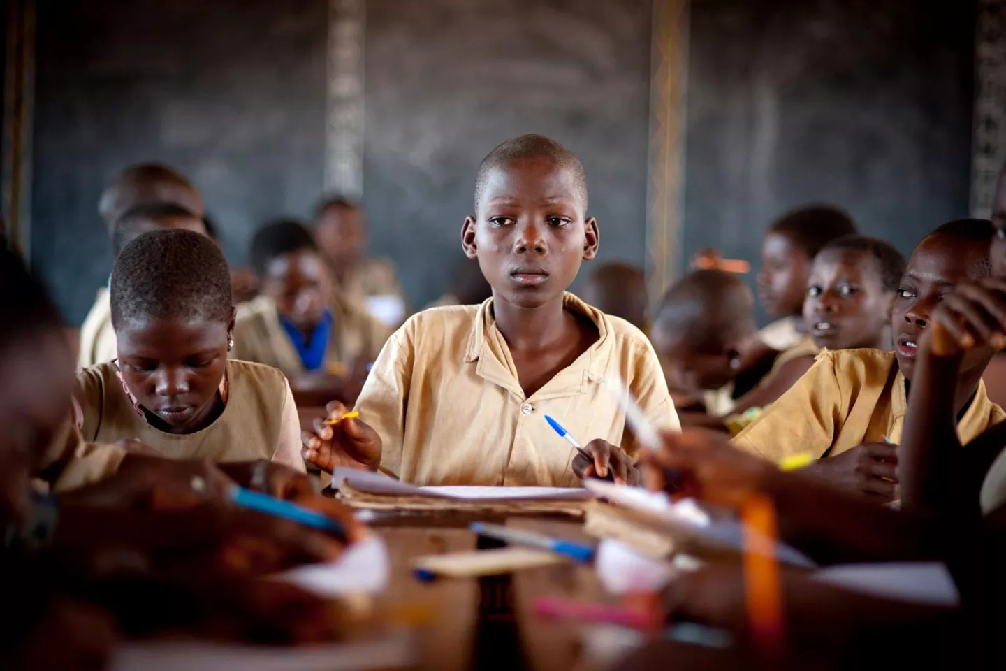 A boy sits amongst fellow students at a desk in his classroom