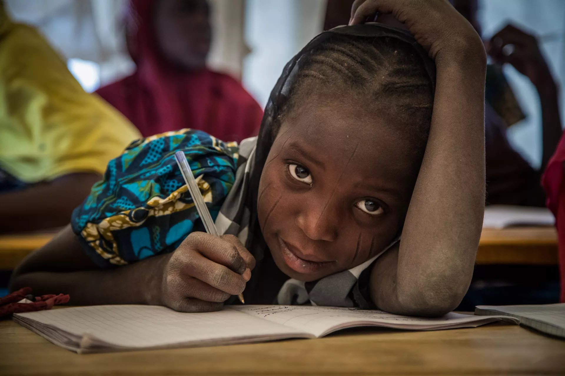 Girl looks up from writing during a class