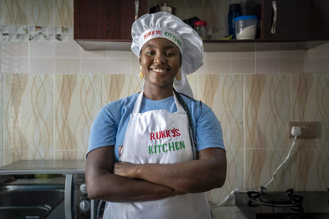 Young woman wearing her chef attire, smiling with her arms crossed