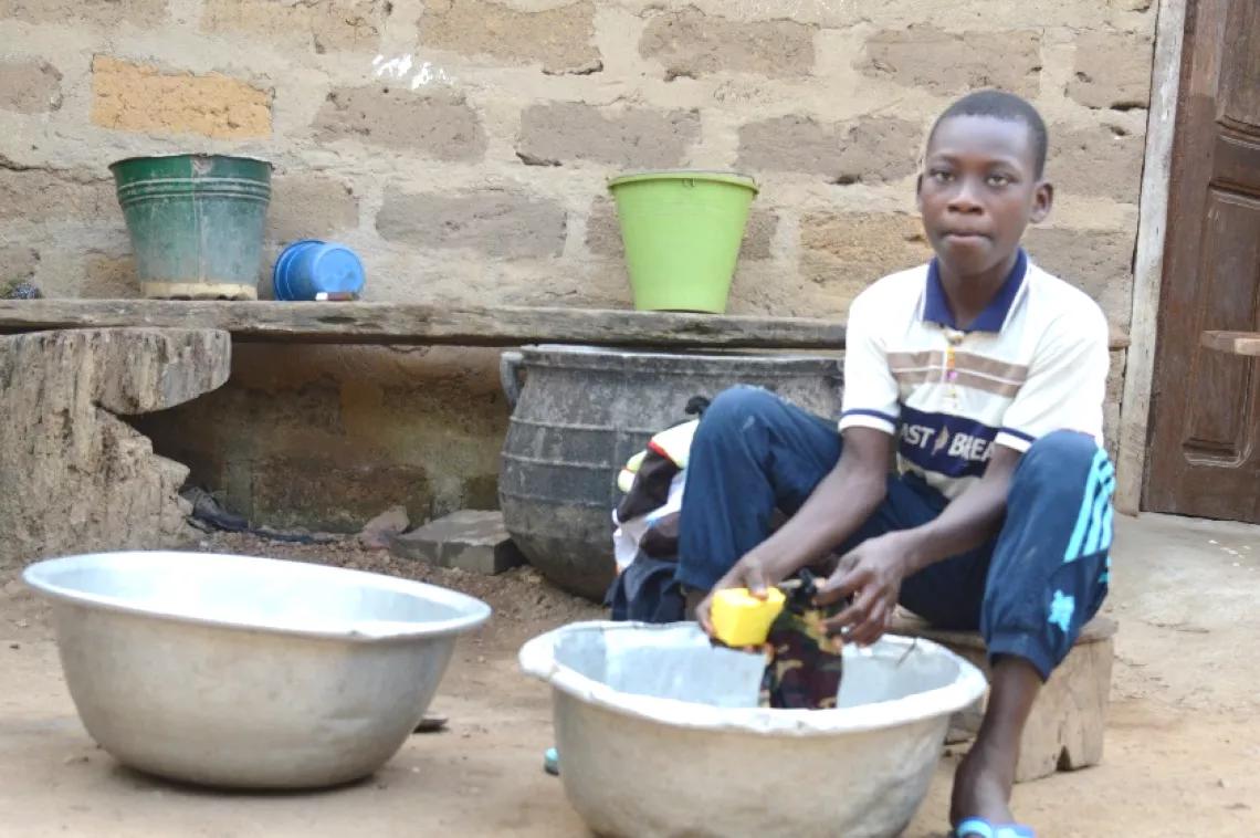 A young boy sitting outside doing his laundry