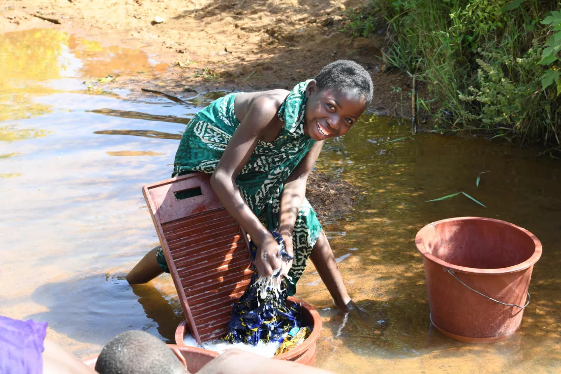 Une jeune fille qui fait sa lessive en souriant