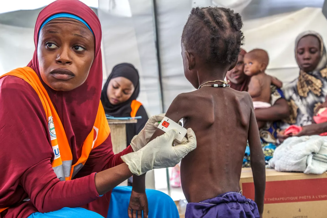 On 10 August 2016, Aisha Muhammad Abdulahi, 25yrs, a Community Manager for Severe Acute Malnutrition is screening and treating Ajija Lawani, 6yr, for Severe Acute Malnutrition (SAM) at one of the health centers UNICEF is supporting in Muna garage IDP camp, Maiduguri, Borno state, northeast Nigeria. 
