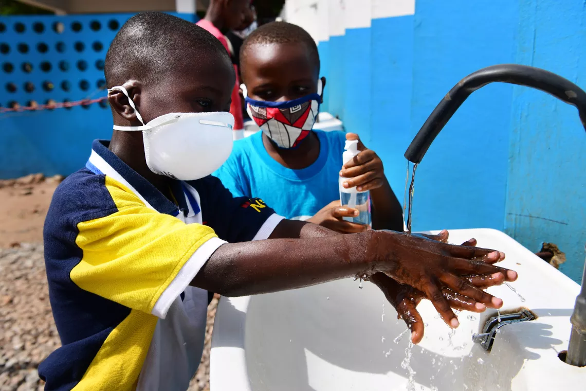 Deux gar&ccedil;ons se lavent les mains en portant des masques de protection contre le coronavirus