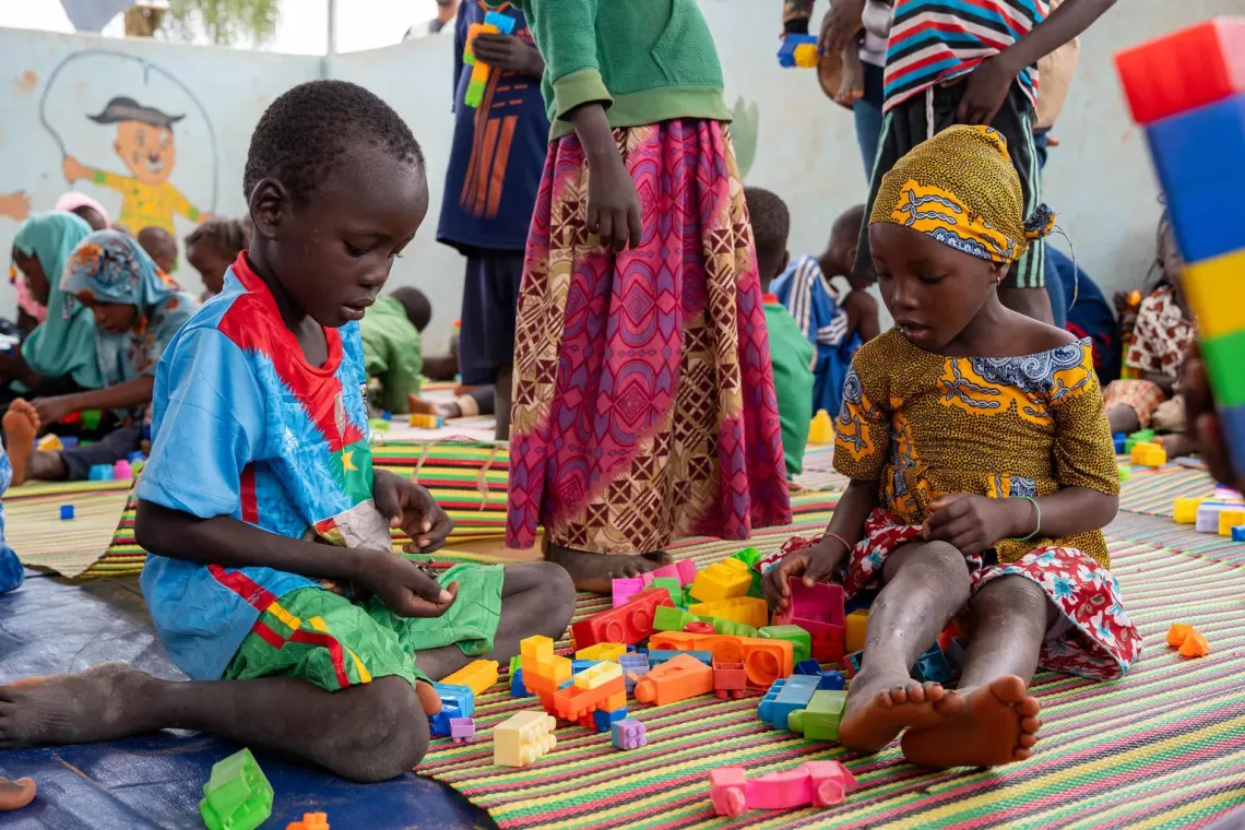 A little boy (left) and a girl (right) playing with colorful blocks and toys