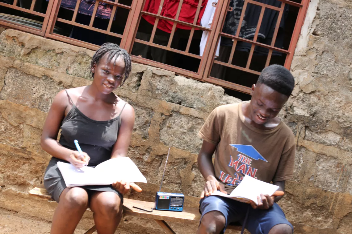 Twins sitting and doing their school work by listening to the radio