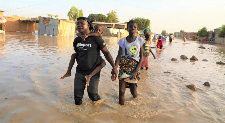 U-Reporters carrying children in the middle of the floods