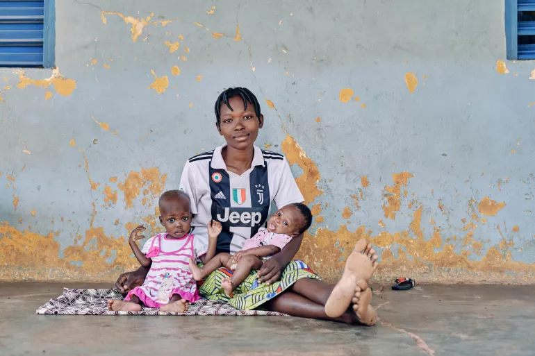 A mother sitting on the floor with her two small children