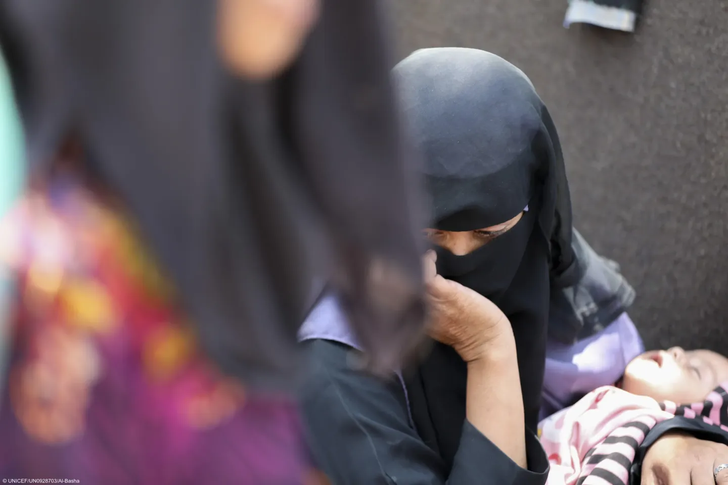 A displaced woman, holds her child at an IDP site in the Jabal Habashi district, Taiz