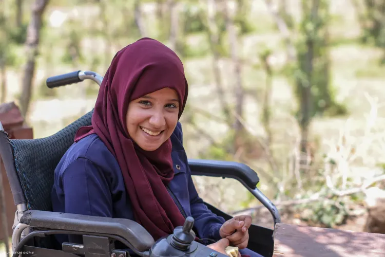 A girl with disability smiles to the camera.