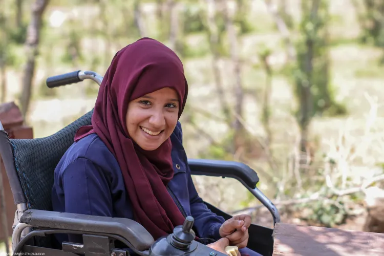 A girl with disability smiles to the camera.