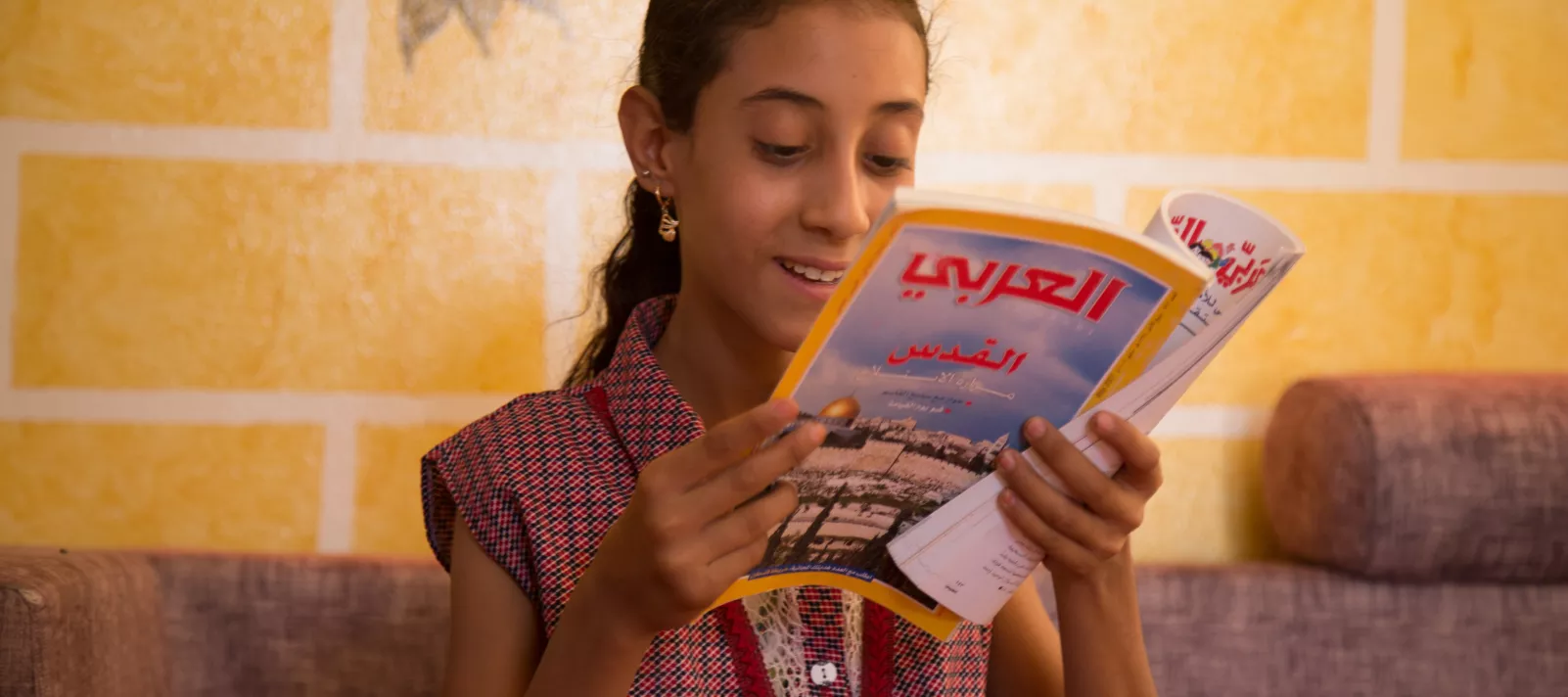 طفلة تقرأ في مجلة في أحد مساحات اليونيسف الصديقة للطفل في محافظة شبوة.