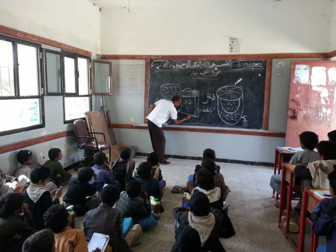 A teacher shows his students all the methods of safe water storage to prevent the spread of waterborne disease