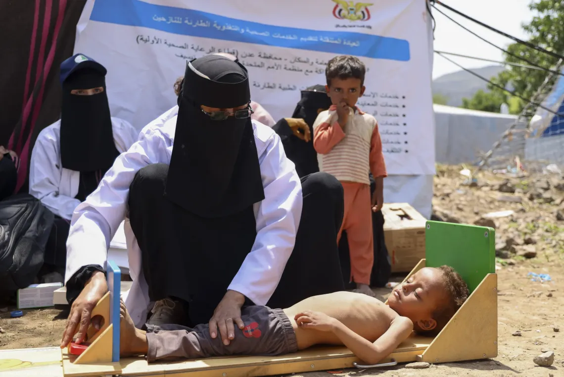 At a mobile health clinic in Aden Governorate, Yemen, a healthcare worker measures the length of a young child lying on a height board to screen for malnutrition and deliver essential emergency health services.