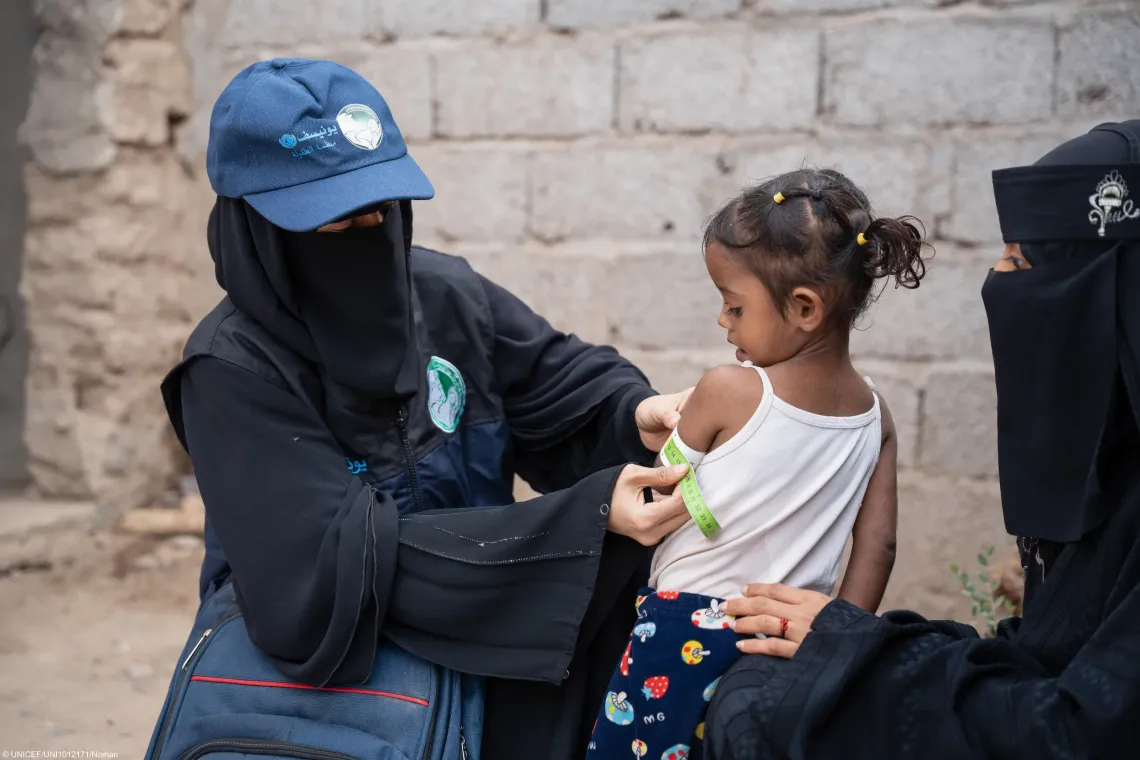 Community health and nutrition volunteer measures the Mid-Upper Arm Circumference (MUAC) of two-year-old girl during a household visit in Yemen.