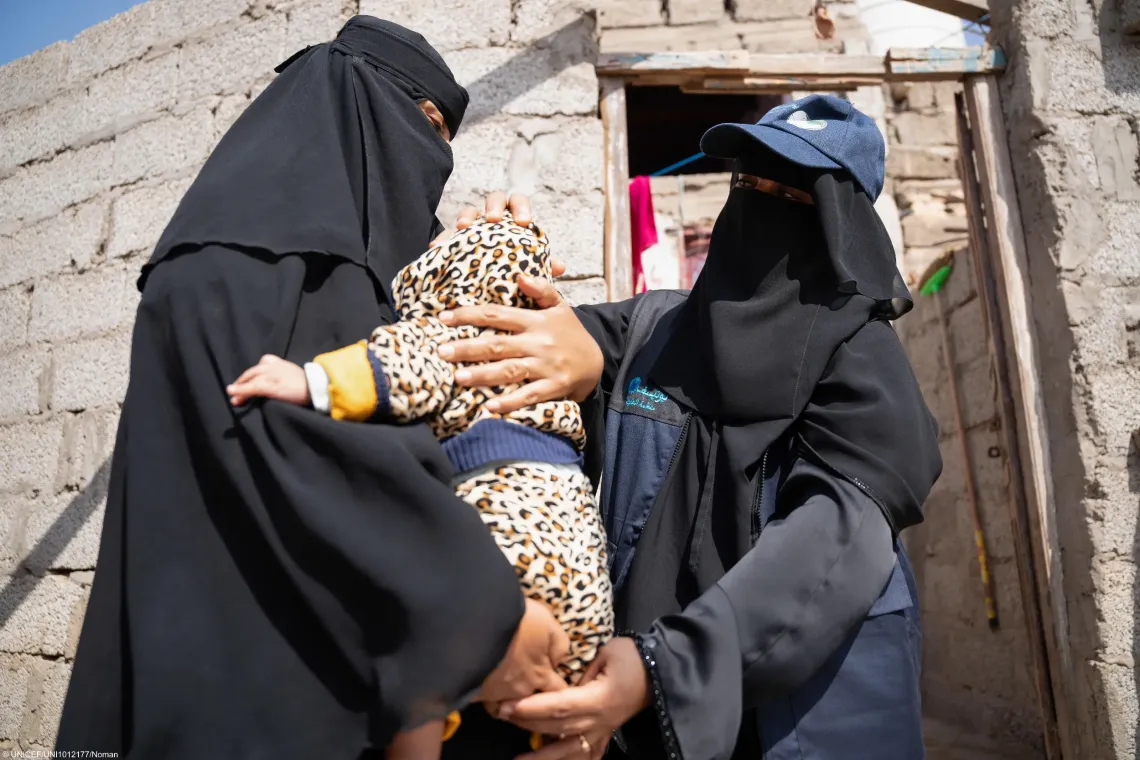 Community health and nutrition volunteer checks on the baby, during a home visit in Yemen.