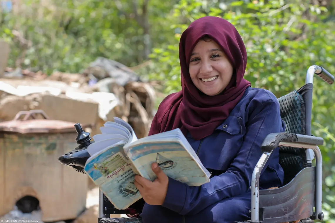 A disabled girl holds her schoolbook with happiness.