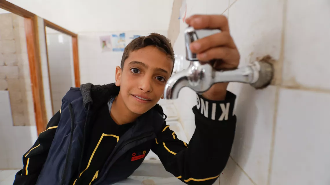 a boy using a water faucet 